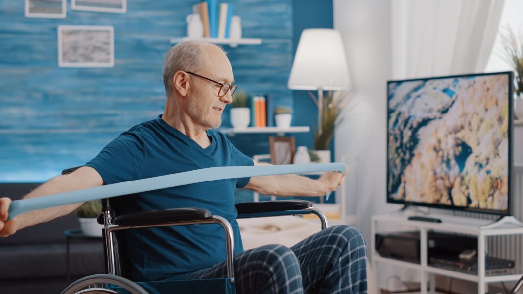 Elder person with disability stretching resistance band to exercise