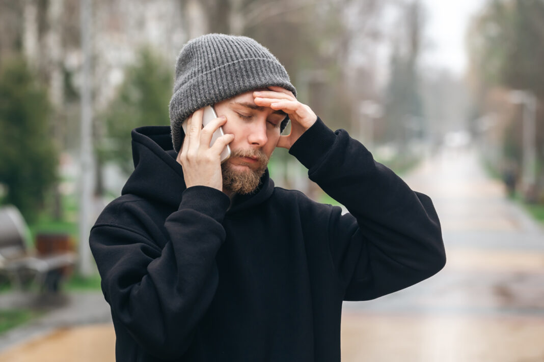 Man talking on the phone and holding his head, bad news.